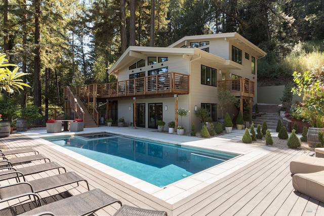 rear view of house featuring a deck, stairway, an outdoor pool, and a patio