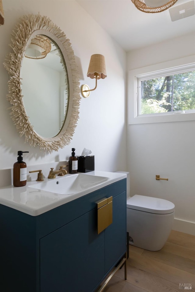 half bathroom featuring toilet, wood finished floors, and vanity