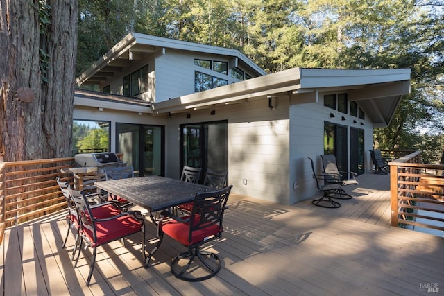 wooden terrace featuring outdoor dining space and a grill