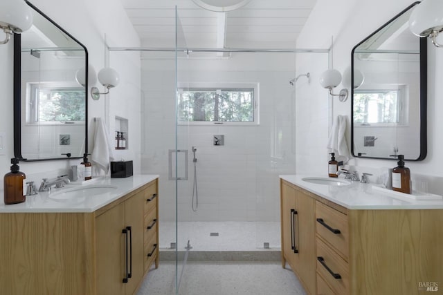 bathroom with a stall shower, a healthy amount of sunlight, and a sink