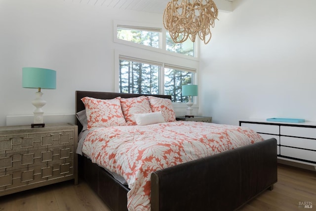 bedroom featuring an inviting chandelier and light wood-style flooring