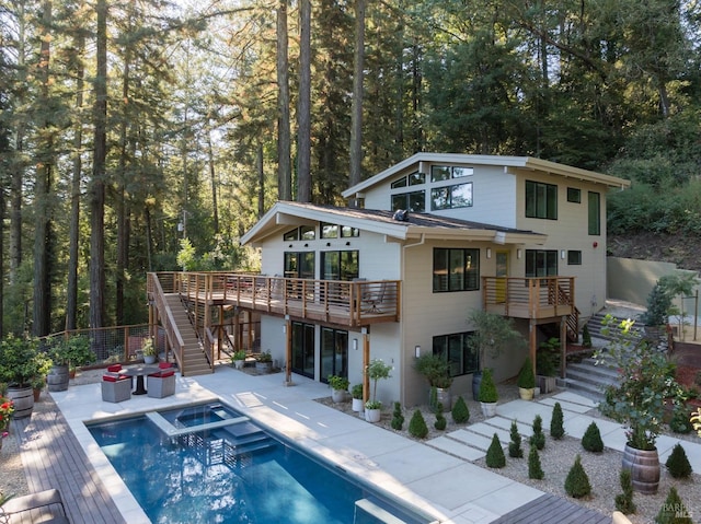 rear view of property featuring a pool with connected hot tub, a patio area, fence, a deck, and stairs