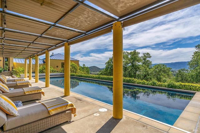 outdoor pool with a patio, a mountain view, and an outdoor hangout area