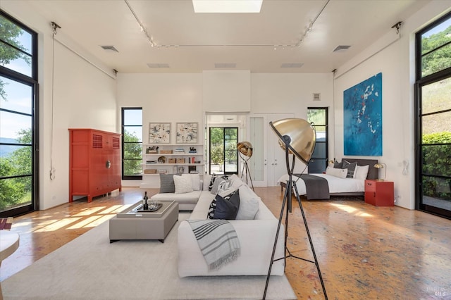 living area featuring track lighting, a skylight, visible vents, and a towering ceiling