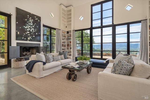 living area featuring a mountain view, a high ceiling, finished concrete floors, and a fireplace