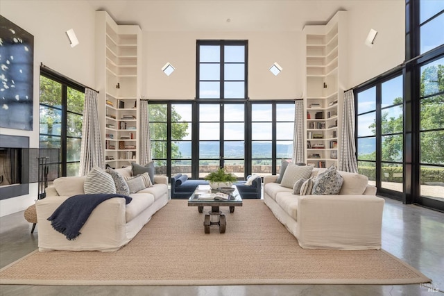 living room with finished concrete floors, a fireplace, a high ceiling, and built in features