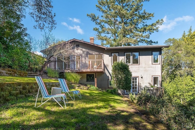 back of property featuring a yard, a chimney, and a wooden deck