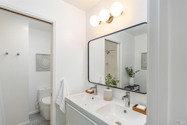 bathroom with baseboards, a sink, toilet, and double vanity