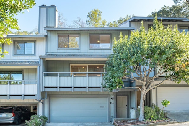 townhome / multi-family property with a garage, concrete driveway, roof with shingles, and a chimney