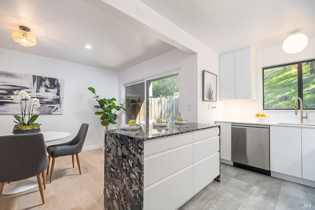 kitchen with stainless steel dishwasher, modern cabinets, a sink, and white cabinetry