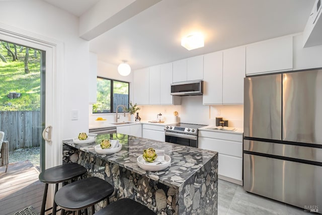 kitchen featuring stainless steel appliances, white cabinetry, a sink, and a breakfast bar area