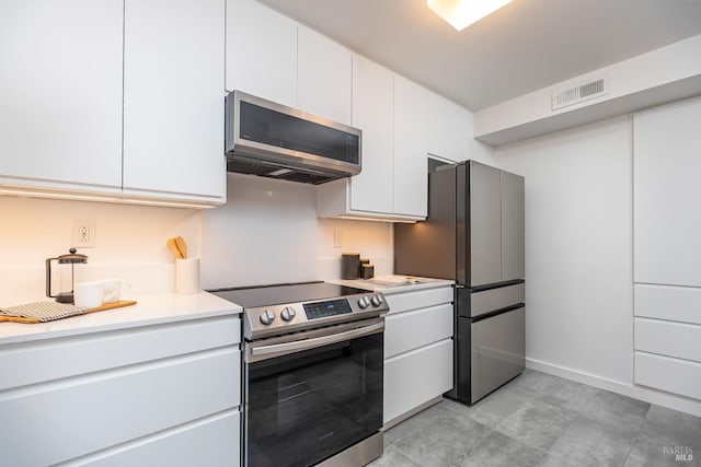 kitchen featuring appliances with stainless steel finishes, light countertops, visible vents, and white cabinetry