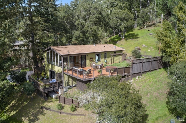 rear view of house with fence, a deck, an attached garage, and a lawn