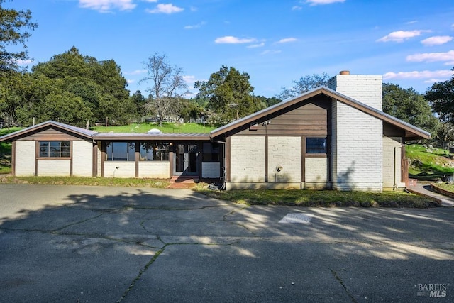 mid-century modern home with brick siding and a chimney