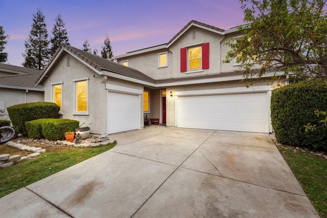 traditional-style home with driveway, a tile roof, and stucco siding