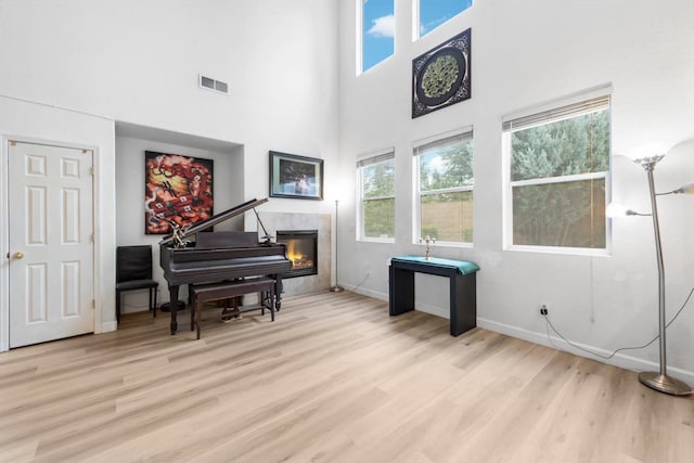 sitting room featuring light wood-type flooring, baseboards, visible vents, and a tile fireplace