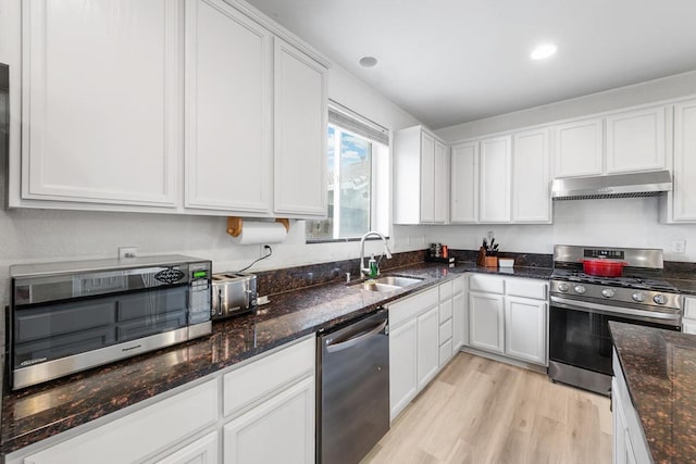 kitchen with under cabinet range hood, a sink, white cabinetry, appliances with stainless steel finishes, and light wood-type flooring