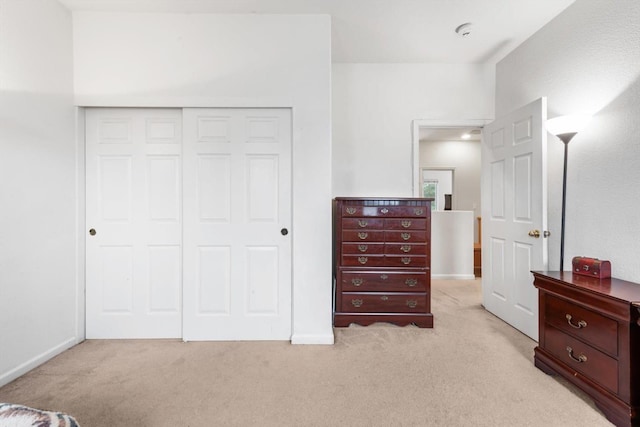 bedroom featuring baseboards, a closet, and light colored carpet