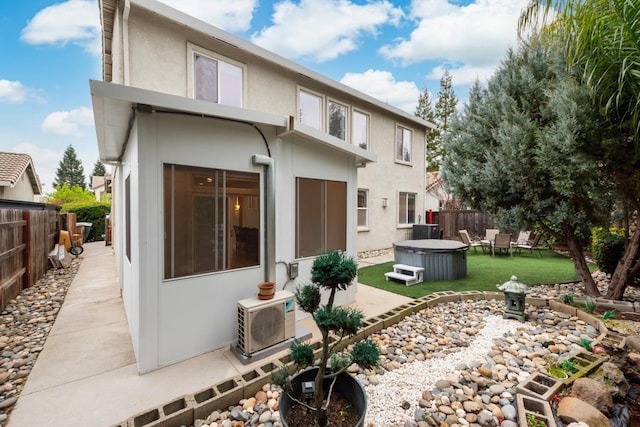 rear view of house with a patio, stucco siding, a fenced backyard, and a hot tub