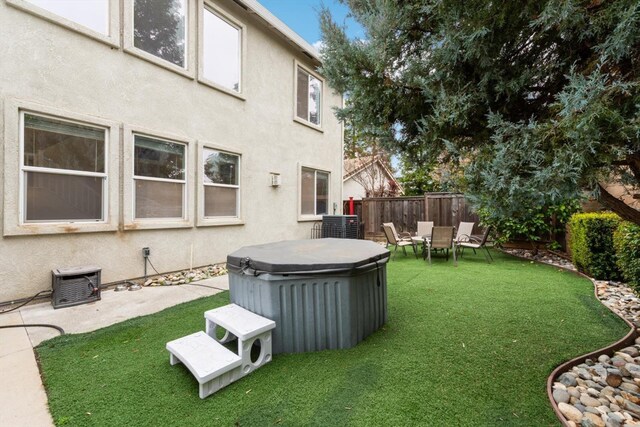 view of yard featuring cooling unit, fence, and a hot tub