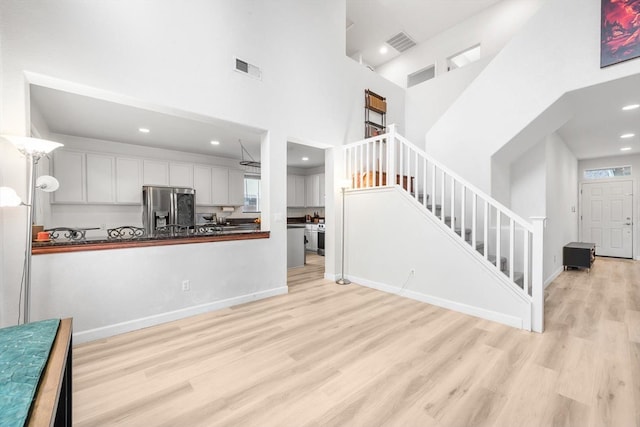 living room featuring visible vents, a high ceiling, stairway, and wood finished floors