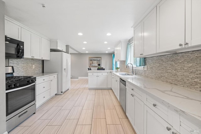 kitchen featuring a peninsula, white cabinetry, appliances with stainless steel finishes, and a sink