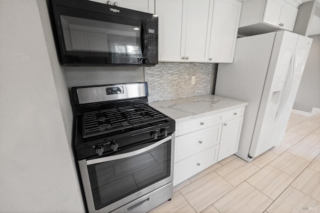 kitchen with black microwave, white refrigerator with ice dispenser, light stone countertops, stainless steel range with gas cooktop, and white cabinetry