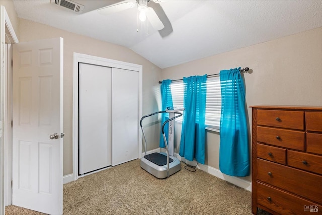 workout area featuring lofted ceiling, carpet floors, visible vents, and a ceiling fan