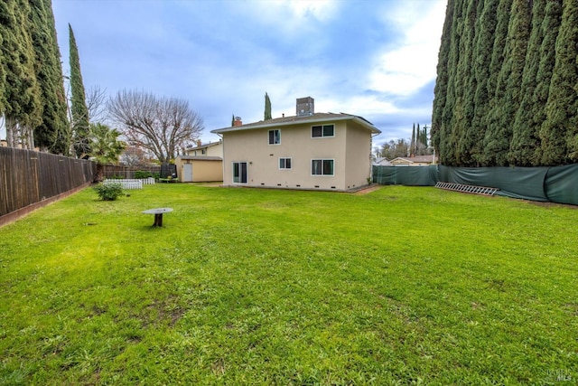 back of house with a fenced backyard, a chimney, crawl space, a yard, and stucco siding