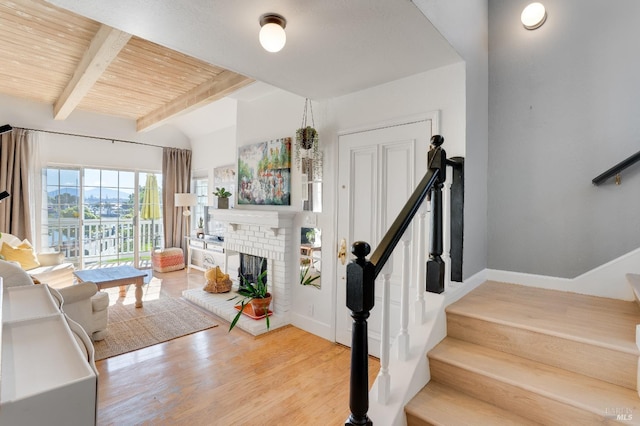 living area featuring wood finished floors, wood ceiling, baseboards, stairs, and a brick fireplace