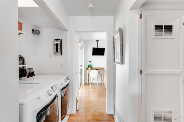 hallway with baseboards, visible vents, light wood-style flooring, and washing machine and clothes dryer