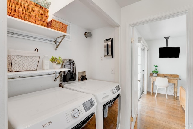 laundry room featuring light wood finished floors, laundry area, and separate washer and dryer