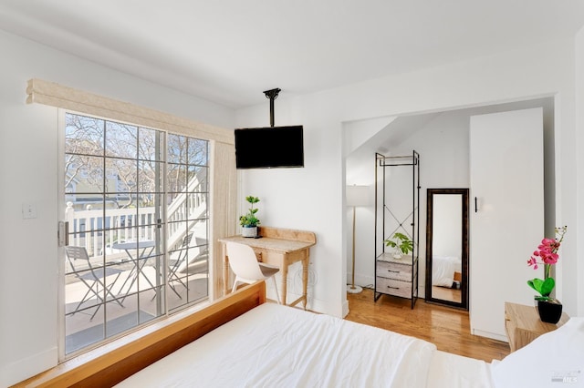 bedroom with access to outside, baseboards, and wood finished floors