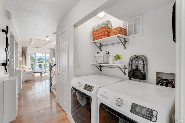 laundry room featuring a textured ceiling, laundry area, separate washer and dryer, and light wood-style floors