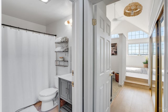 ensuite bathroom with ensuite bathroom, toilet, wood finished floors, vanity, and vaulted ceiling