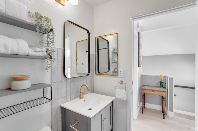 bathroom with tile walls, vanity, baseboards, and wood finished floors