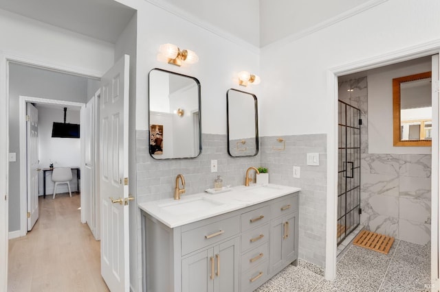 bathroom featuring a stall shower, wood finished floors, a sink, and double vanity