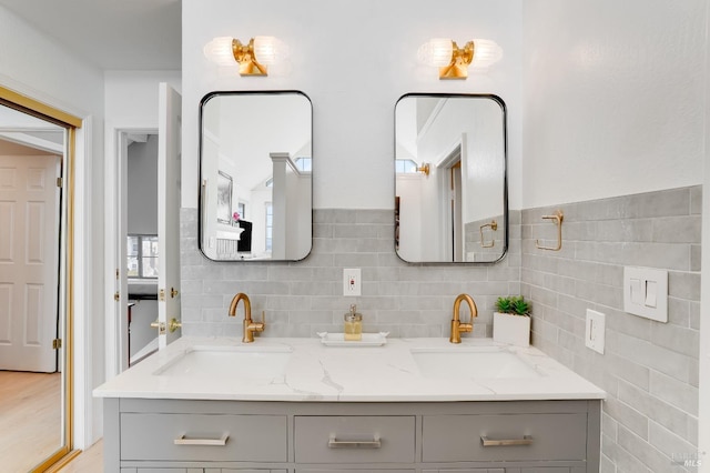 full bathroom featuring double vanity, tile walls, and a sink