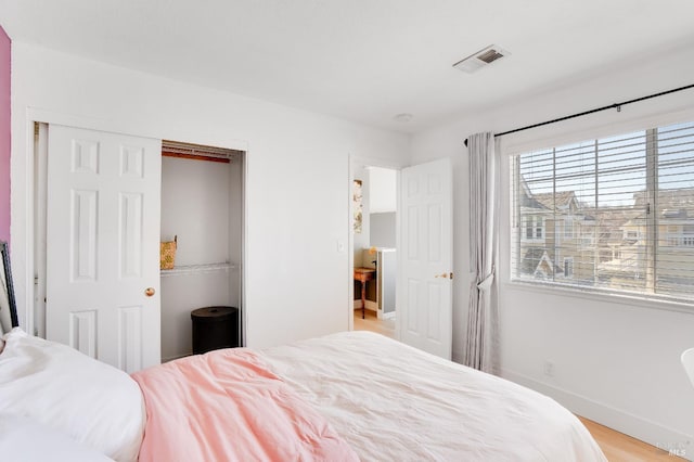 bedroom featuring a closet, visible vents, light wood finished floors, and baseboards