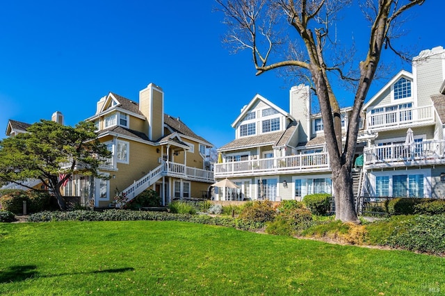 rear view of property featuring stairs, a lawn, and a chimney