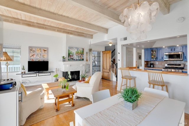 dining area featuring visible vents, wood ceiling, beamed ceiling, light wood-style floors, and a fireplace