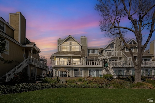 rear view of property featuring stairs, a lawn, and a chimney