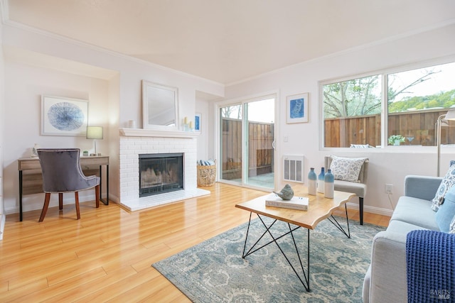 living area featuring a fireplace, visible vents, ornamental molding, wood finished floors, and baseboards