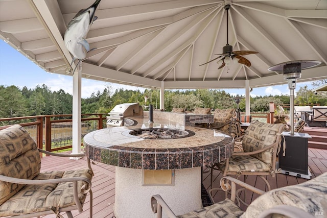 wooden terrace with a fire pit, a gazebo, a grill, and a ceiling fan