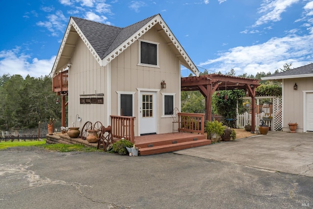 view of front of house with a shingled roof, fence, a deck, and a pergola