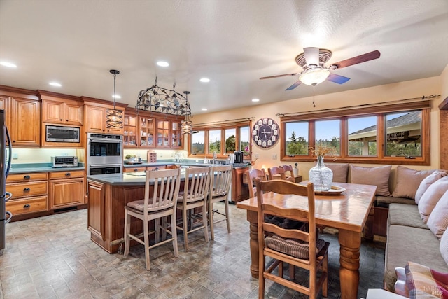 kitchen with a kitchen island, appliances with stainless steel finishes, brown cabinets, a kitchen bar, and glass insert cabinets