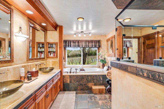 full bath featuring a bath, stone tile floors, double vanity, and a sink