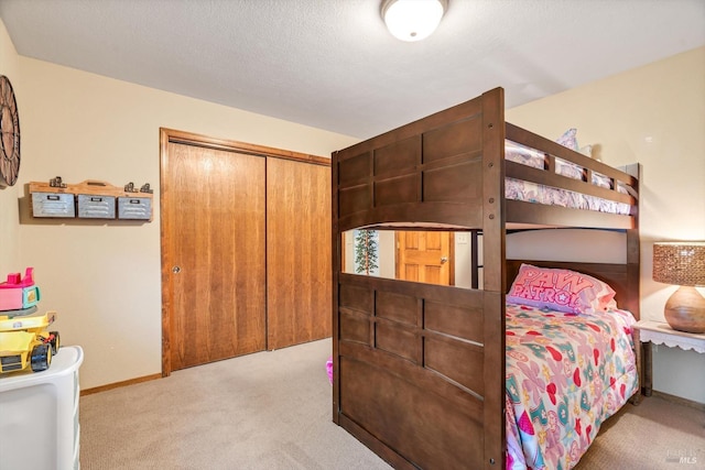 bedroom with a textured ceiling, a closet, carpet flooring, and baseboards