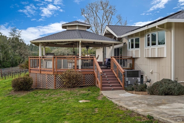 back of property with a gazebo, a lawn, a wooden deck, and roof with shingles