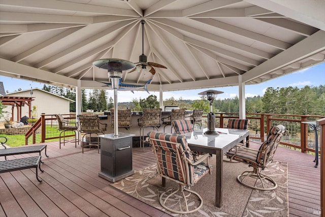 wooden deck with a gazebo, ceiling fan, and outdoor dining space